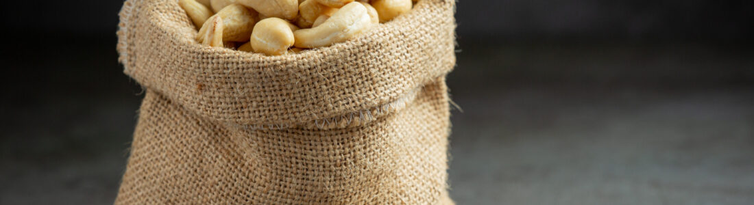 Raw cashews nuts in bag on dark background