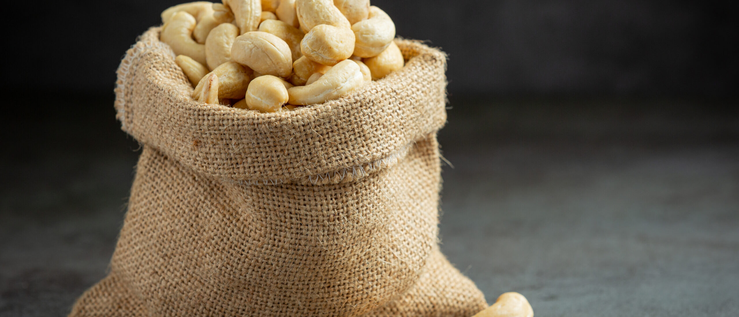 Raw cashews nuts in bag on dark background Raw cashews nuts in bag on dark background