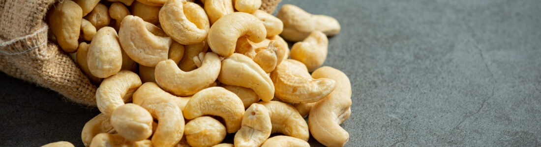 Raw cashews nuts in bag on dark background