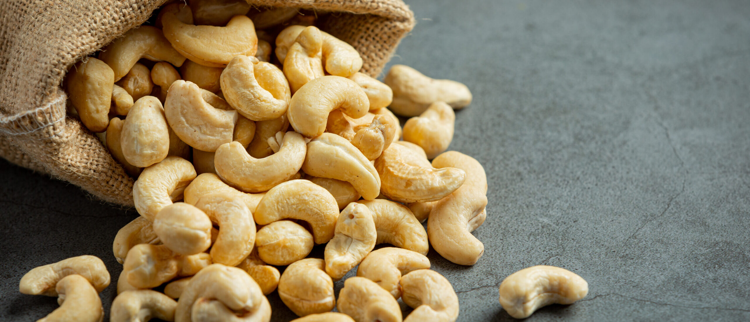 Raw cashews nuts in bag on dark background Raw cashews nuts in bag on dark background