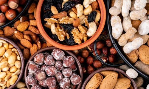 Set of pecan, pistachios, almond, peanut, cashew, pine nuts and assorted nuts and dried fruits in a mini different bowls and black pan. top view.