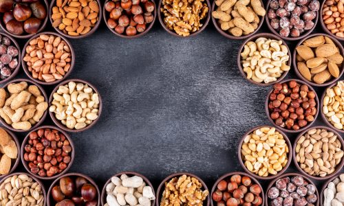 Some of assorted nuts and dried fruits with pecan, pistachios, almond, peanut, in a mini different bowls on black stone background, top view. copy space for text